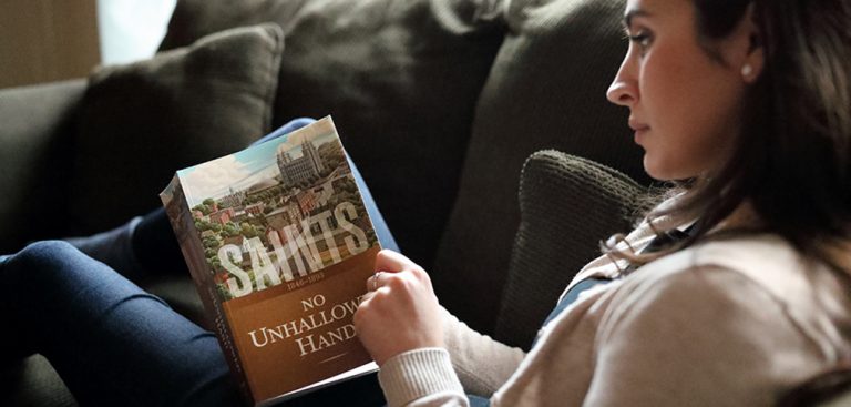 A woman reading a copy of the book: "Saints"