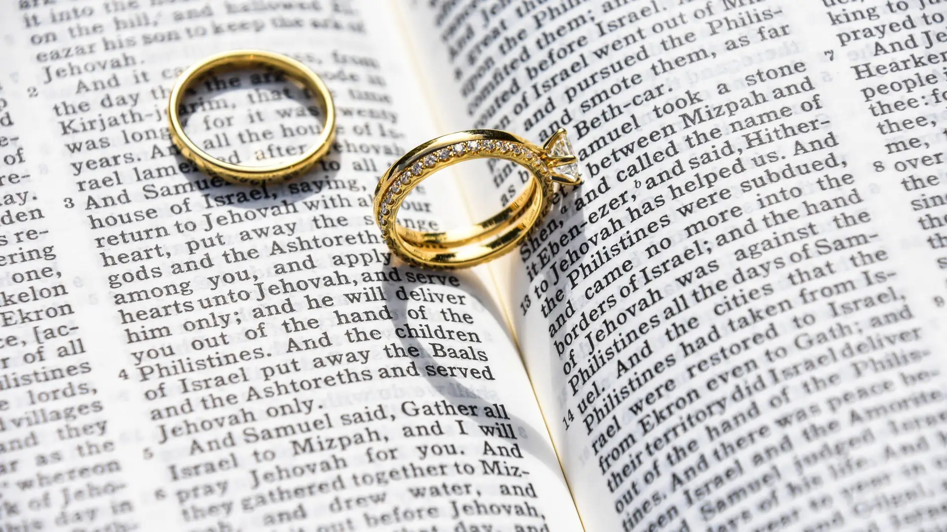 Two wedding rings on top of open pages of the Bible.