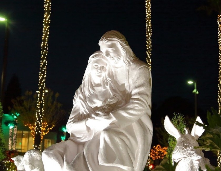 White statues of the Navity draped in white light at Oakland Temple Hill at Christmastime.